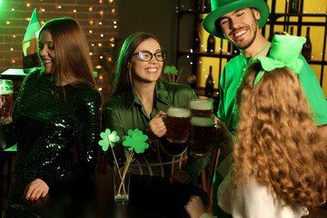 Group of young friends with beer celebrating St. Patrick's Day in pub at night