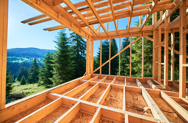 Wooden frame house under construction near forest. Beginning of new construction of cozy house on...