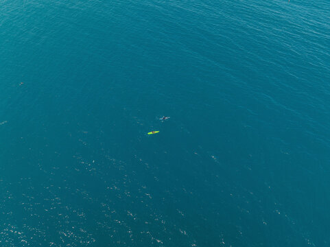 Aerial view of a two tiny people canoeing into the sea in Milazzo, Sicily, Italy.