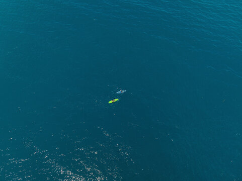 Aerial view of a two tiny people canoeing into the sea in Milazzo, Sicily, Italy.