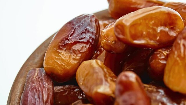 Circular motion Sweet dates in wooden bowl isolated on white background.