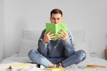 Young man reading book in bedroom