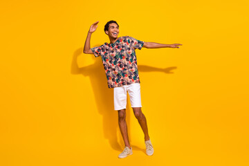 Full body length photo of having fun young man tourist student spend his free time outdoors dancing isolated on yellow color background