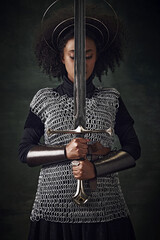 Portrait of young African woman, medieval warrior in chainmail armor with halo-like rings above...