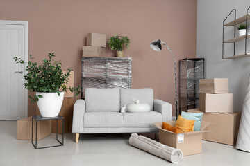 Cardboard boxes, picture and furniture in new living room on moving day