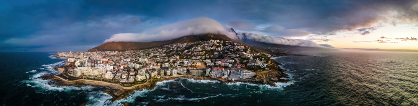 Panoramic aerial view of Bantry Bay and low cloud over Lion’s Head Mountain with Table Mountain in background at sunset, Bantry Bay, Cape Town, South Africa.