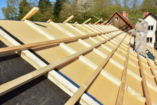Dachdecker beim Verlegen und befestigen der Dachlatten eines Steildachs auf der Holzfaserdämmung für die Eindeckung mit Ziegeln