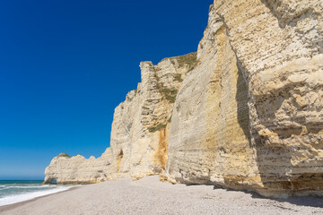Etretat cliffs and beach in the Normandie region of France in a sunny day. Falaise d'amont chalk...