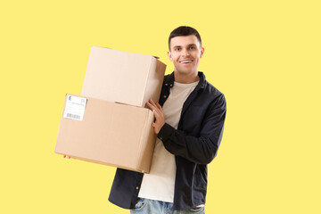 Male online store seller with parcel boxes on yellow background