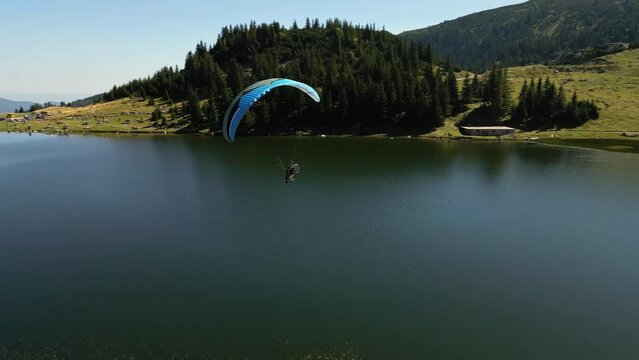 Drone Following a Man Flying Powered Paraglider Over a Beautiful Mountain Lake Landscape Concept of Freedom, Risk Taking, Adventure, Adrenaline. Vranica Mount, Bosnia and Herzegovina, Europe