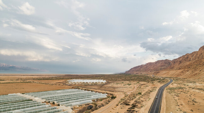 Aerial view of Dead Sea, Israel, Palestine, Bethlehem Governorate with vast arid terrain and greenhouses, agriculture, farms, scenic, and geological formations.