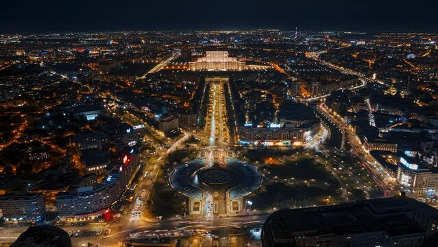 Aerial hyperlapse timelapse drone view of illuminated Palace of the Parliament in city downtown in the night. Multiple districts around