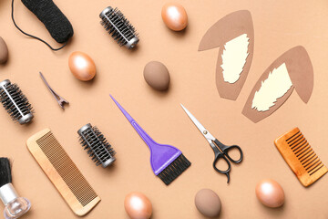 Hairdressing accessories with paper bunny ears and Easter eggs on light brown background