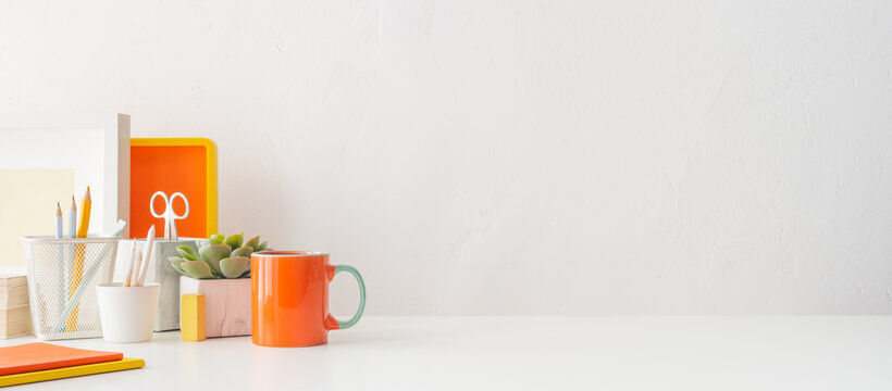 Home office desk with orange office supplies and empty table space for product display.