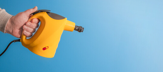 A person is holding a yellow device A vacuum cleaner. A person is holding a yellow steam cleaner....
