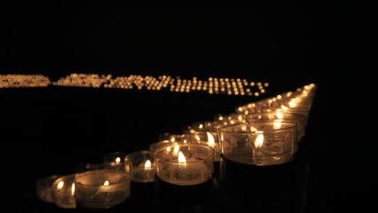 Many burning candles with shallow depth of field in a church.