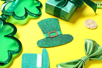 Paper leprechaun hats with eyeglasses, gift box and bow tie on yellow background. St. Patrick's Day...