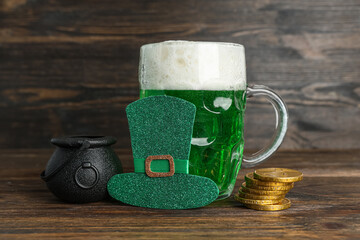 Paper leprechaun hat with pot, mug of green beer and coins on wooden background. St. Patrick's Day...