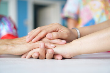Asian woman is in the living room holding hands to encourage, sympathize, and comfort, taking care of a sick person at home. - obrazy, fototapety, plakaty