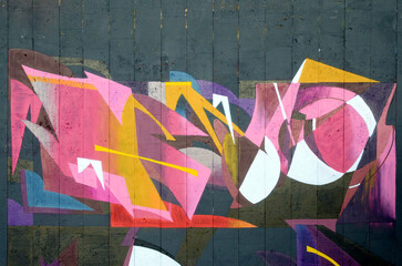 The old wall decorated with paint stains in the style of street art culture. Colorful background of full graffiti painting artwork with bright aerosol outlines on wall. Colored background texture