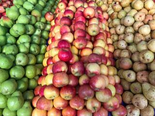 Naklejka na ściany i meble Apples and pears neatly stacked, ready for sale at the bulk market.
