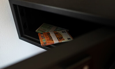 Two packs of euro banknotes lie in an open safe. - 763285411