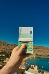 Man holds money against the backdrop of a beach in a warm country. - 763285461