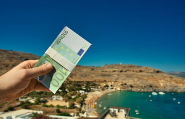 Man holds money against the backdrop of a beach in a warm country. - 763285472