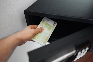 Man puts or takes euro banknotes from a safe. - 763285486