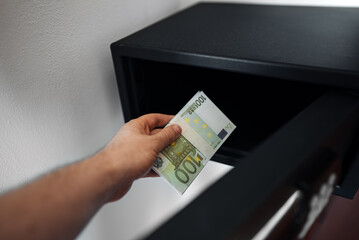 Man puts or takes euro banknotes from a safe. - 763285495