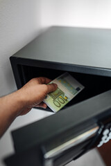 Man puts or takes euro banknotes from a safe. - 763285497