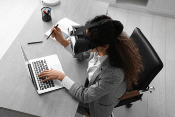 Young African-American businesswoman in VR glasses working in office