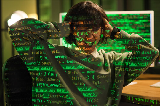 Stressed female programmer with projection of programming code in office at night