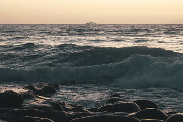 Playa al atardecer con olas rompiendo en las rocas