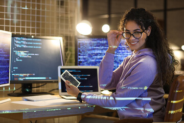 Female programmer with gadgets working in office at night