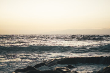 Playa al atardecer con olas rompiendo en las rocas