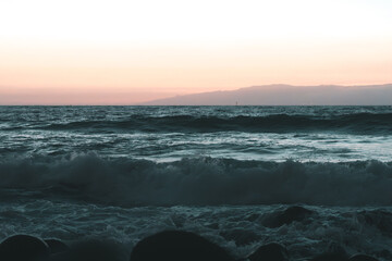 Playa al atardecer con olas rompiendo en las rocas