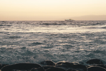 Playa al atardecer con olas rompiendo en las rocas
