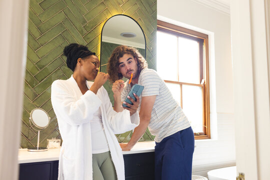 A diverse couple is engaged in their morning routine, brushing teeth in the bathroom