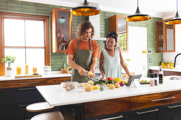 A diverse couple is preparing meal together in a modern kitchen