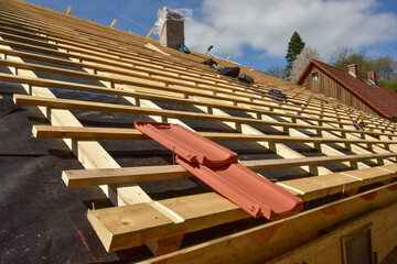 Dachdecker beim Verlegen und befestigen der Dachlatten eines Steildachs auf der Holzfaserdämmung...