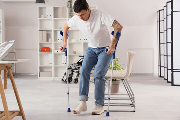 Injured young man after accident with crutches walking in clinic