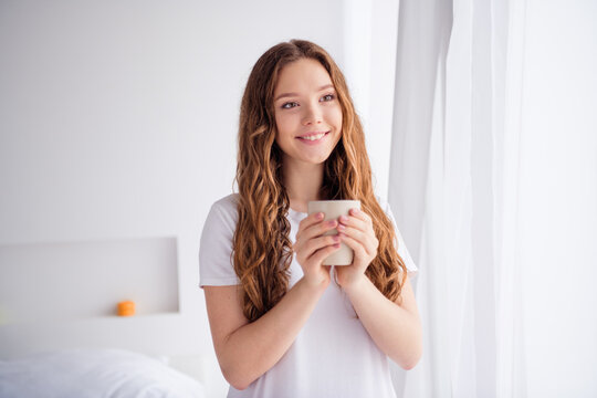 Photo of pretty cheerful female person toothy smile hands hold fresh coffee mug look window inspiration pastime bedroom flat indoors