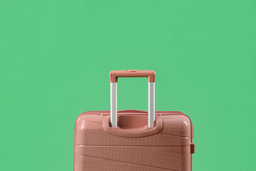 Pink suitcase on green background, closeup