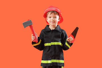 Cute little firefighter with toy tools on orange background