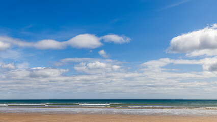 Beach of St. Andrews, Scotland, stretches out with its golden sands meeting the calm sea under a...
