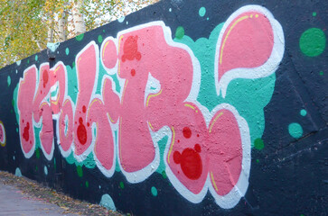The old wall decorated with paint stains in the style of street art culture. Colorful background of full graffiti painting artwork with bright aerosol outlines on wall. Colored background texture