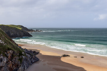 Fototapeta na wymiar A dramatic view of Durness Beach in Scotland, where rugged cliffs meet the pristine sands and the emerald waves of the Atlantic