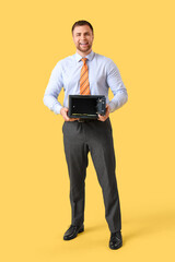 Happy young man with safe box and money on yellow background