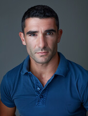 Obraz premium This image captures a handsome man in a blue polo shirt with an intense gaze and confident expression, representing strength and determination